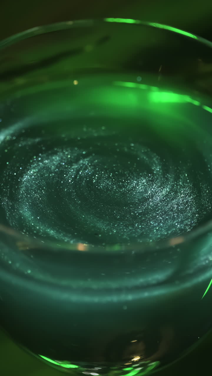 líquido verde con espiral de brillo en un vaso