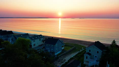 los colores del atardecer se reflejan en las olas del océano con vistas a las casas de la playa.