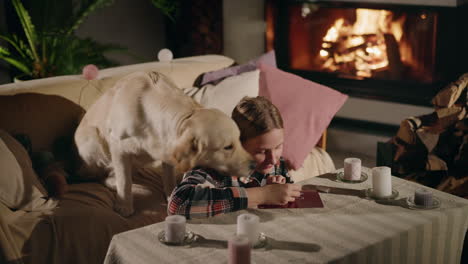 girl drawing with dog at home near fireplace