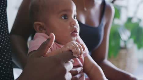 close up of baby daughter holding fathers finger as they sit at home together