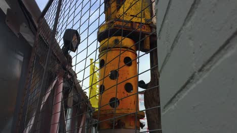 wide angle looking through fence upwards at a rotating hydraulic rotary drilling rig