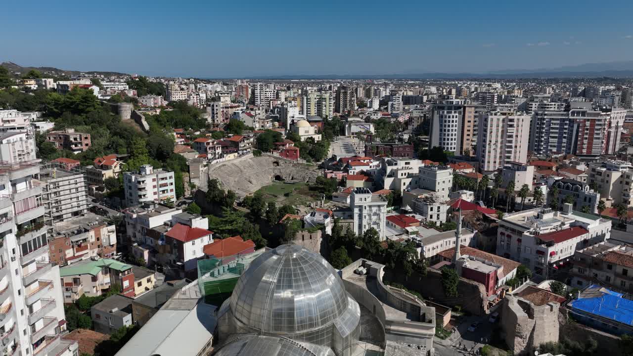 A vibrant cityscape of Durrës, Albania, captured under bright sunlight. The scene showcases the historical urban architecture and lively streets, reflecting the energy and charm of the city.