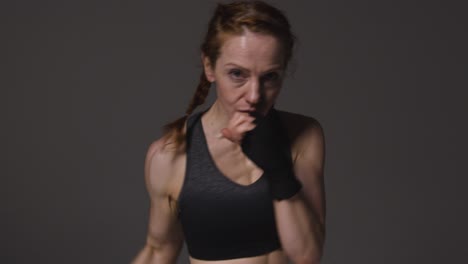 studio portrait of mature woman wearing gym fitness clothing exercising sparring at camera 4