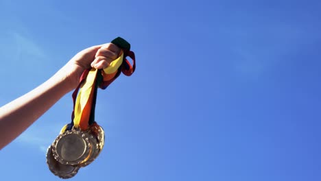 Hand-holding-medals-against-blue-sky-4k