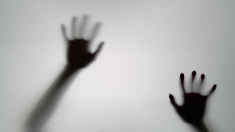 Silhouette of Hands Reaching Through a Semi-Transparent Surface