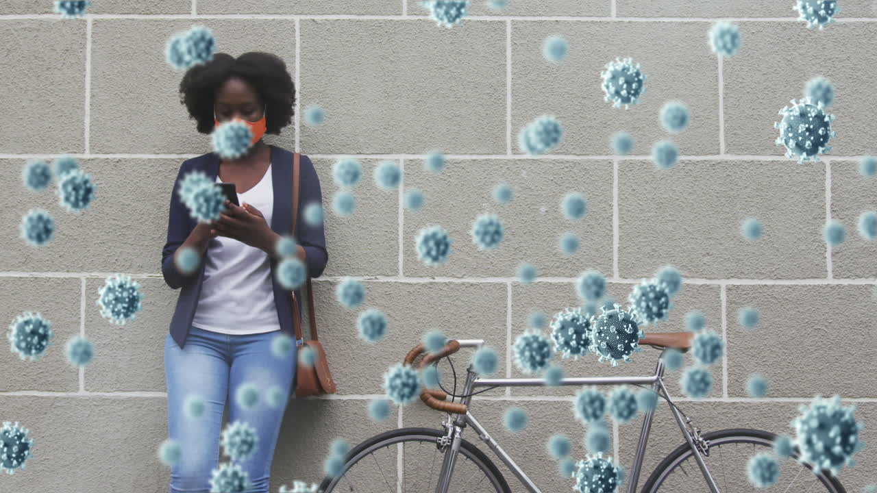 animación de células de covid 19 sobre una mujer afroamericana que usa un teléfono inteligente en una máscara facial