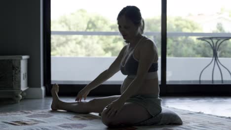 mujer embarazada tranquila practicando yoga en casa