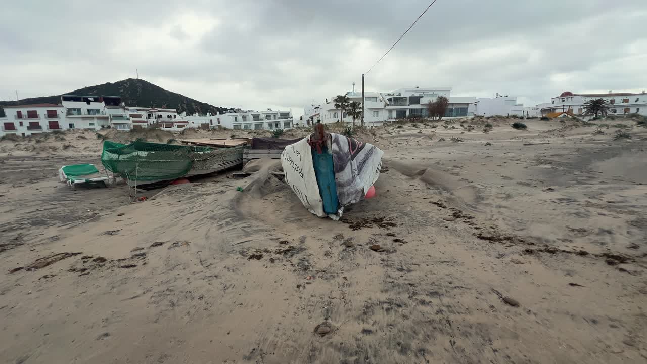 Weathered fishing boats sit on the sandy shore, embodying the rustic allure and gradual deterioration of equipment in a fishing village