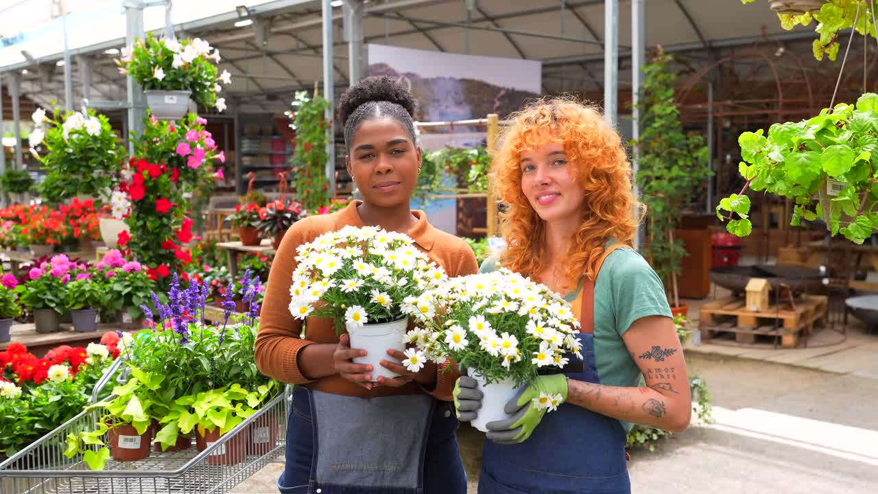 Due donne che tengono dei fiori in un vivaio
