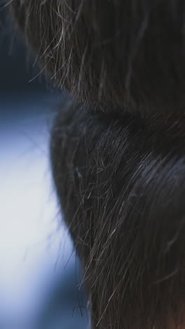 cu shot, slow motion: skilled hairdresser does stylish haircut to young client with black healthy hair using modern golden machine in salon extreme closeup