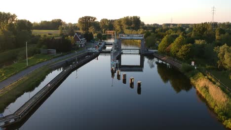 water lock with trees reflection during golden hour in ascending drone view