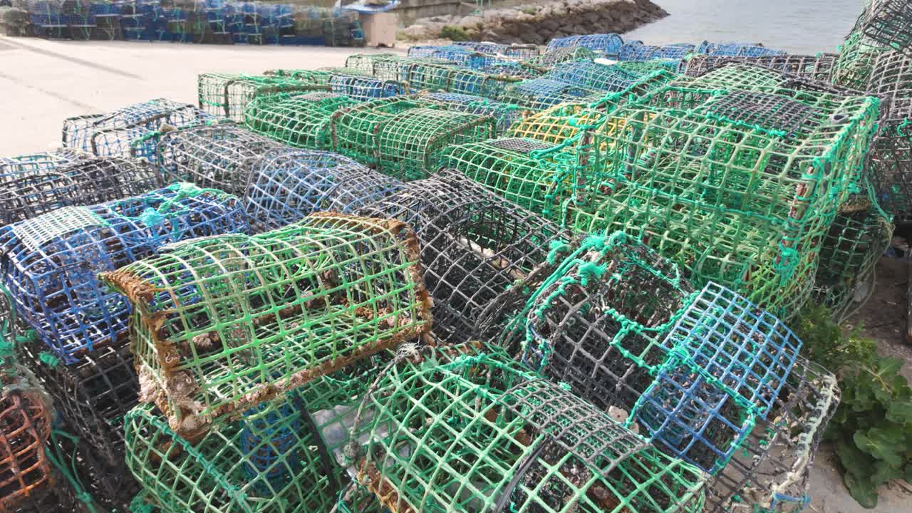 Fishing nets and lobster trap equipment stacked at the fishing harbor in Alvor, Portugal, under bright sunlight
