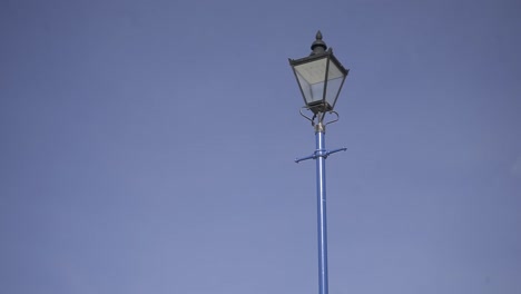 blue metal street lamp stands prominently against a clear blue sky, creating a striking urban scene