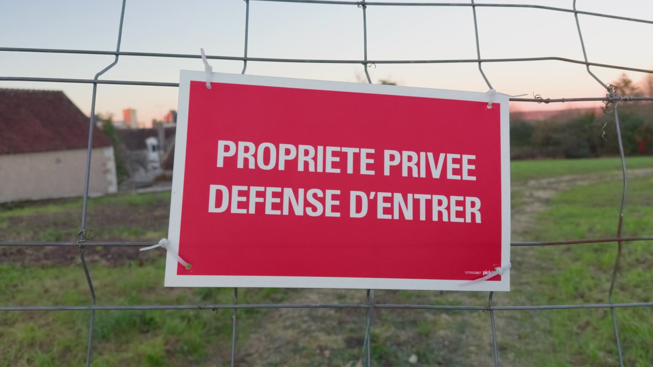 Cartello di proprietà privata su una recinzione esterna che indica accesso limitato e cautela.