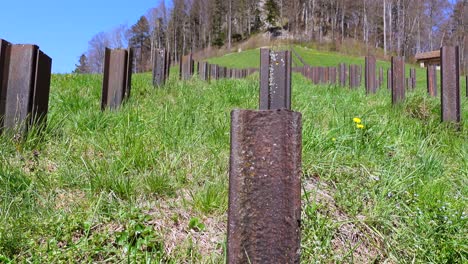 Slow-pan-shot-showing-rusty-Anti-Tank-iron-barriers-on-overgrown-mountain-during-sunny-day-and-blue-sky-in-Switzerland