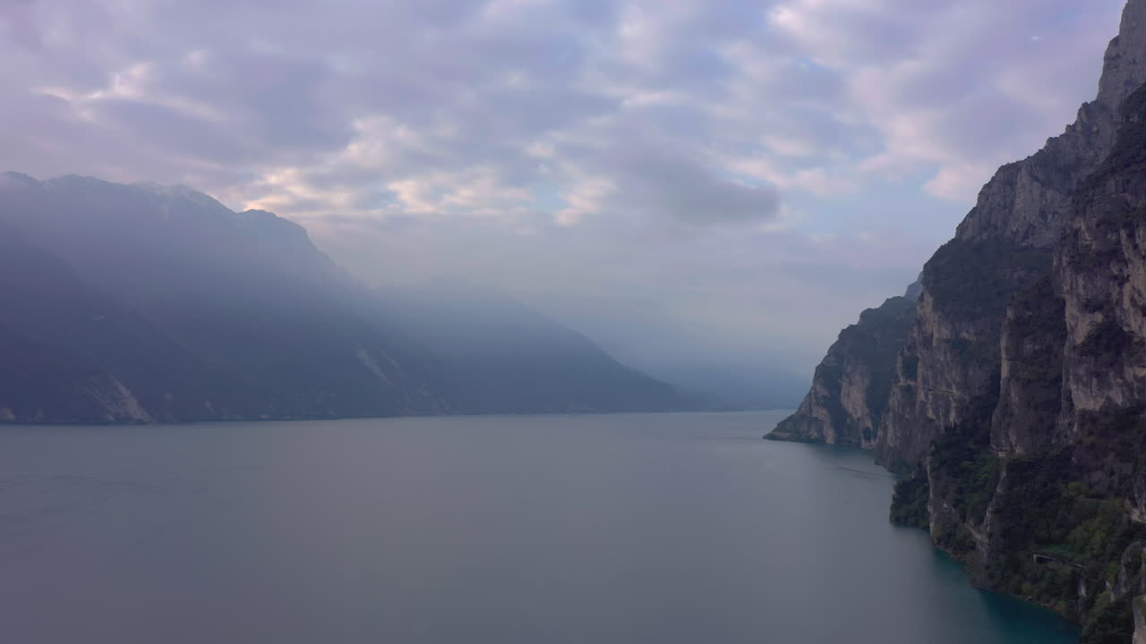 toma aérea del lago de garda y las montañas circundantes cubiertas por una hermosa niebla matutina