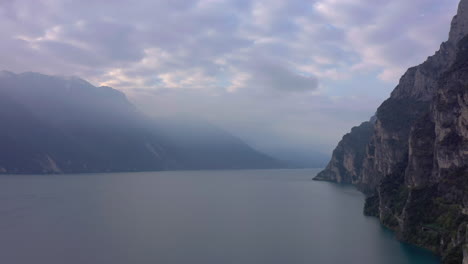 Dolly-out-aerial-shot-of-lake-Garda-and-the-surrounding-mountains-cover-in-beautiful-morning-fog