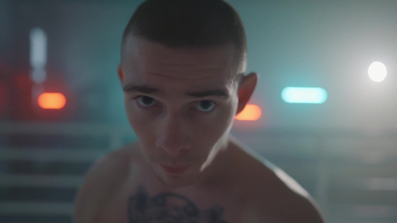 Intense Young Boxer Looking at Camera in a Dark, Neon-Lit Ring