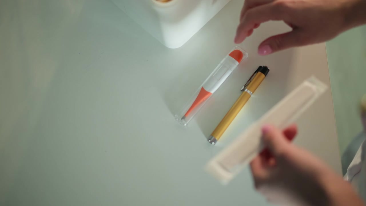 Paramedic inspecting packaged thermometer and pen on glossy surface, closeup of hand unfolding sterile wrapper, soft clinical lighting, focused calm preparation for patient care at home