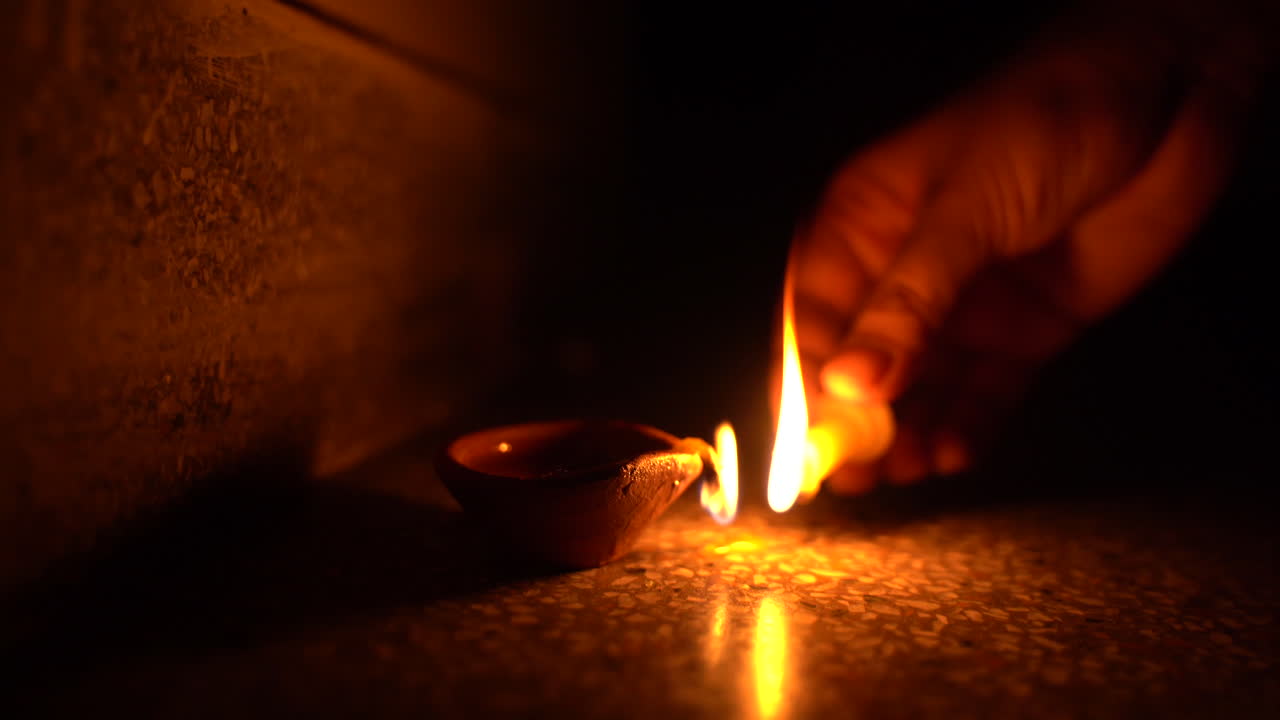 high flames rising from a diya as a girl attempts to ignite it with candle on Diwali night, auspicious festival of light celebrated by Hindus in India