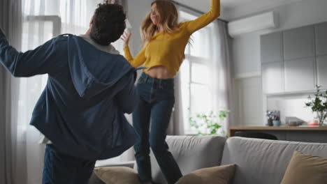 happy husband wife jumping sofa in luxury house closeup. carefree couple dancing