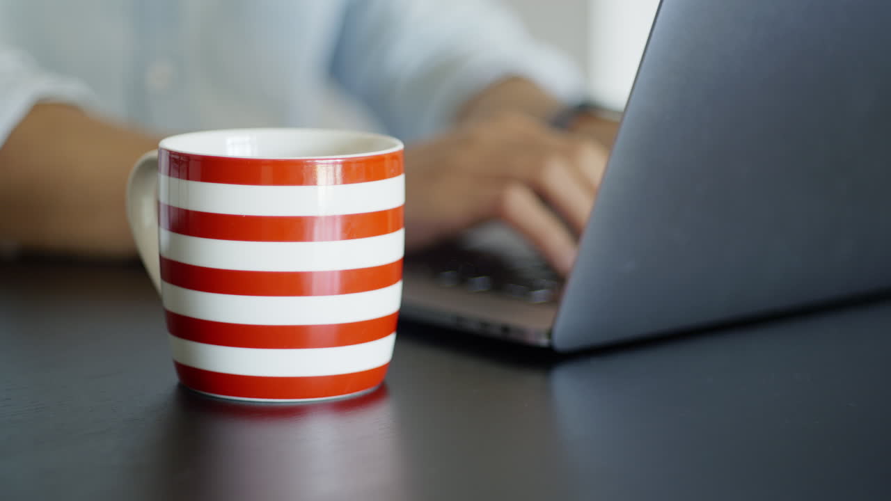 tomando café matutino mientras trabaja desde casa con una laptop