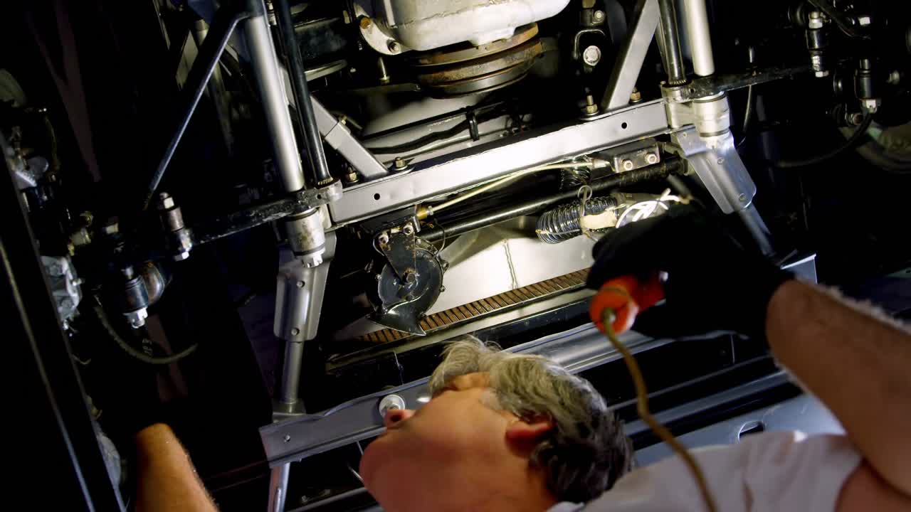 mecánico masculino haciendo servicio a un coche en el garaje 4k