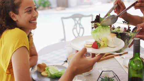 Feliz-Mujer-Latina-Sosteniendo-Un-Plato,-Con-Amigos-En-Una-Cena-En-El-Patio