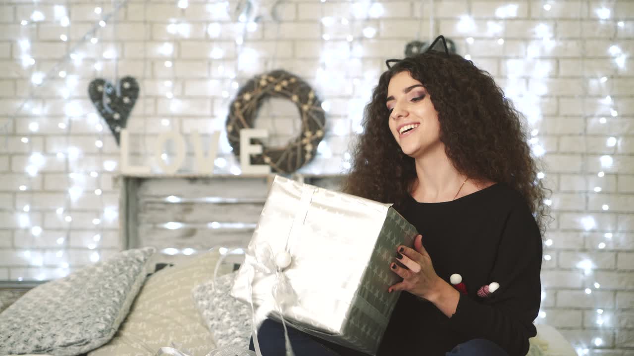 Gift Box New Year Day Celebration. Young attractive woman with gift box near fireplace