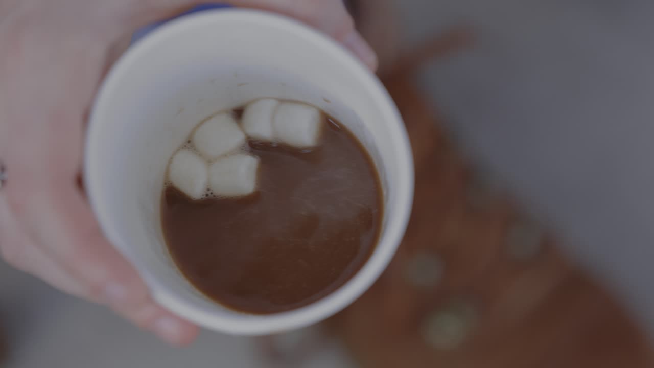 여자가 뜨거운 카카오에 마쉬멜로를 고 마시기 위해 들어갑니다.