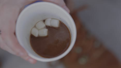 Woman-stirs-marshmellows-in-hot-cocoa-and-lifts-up-to-drink