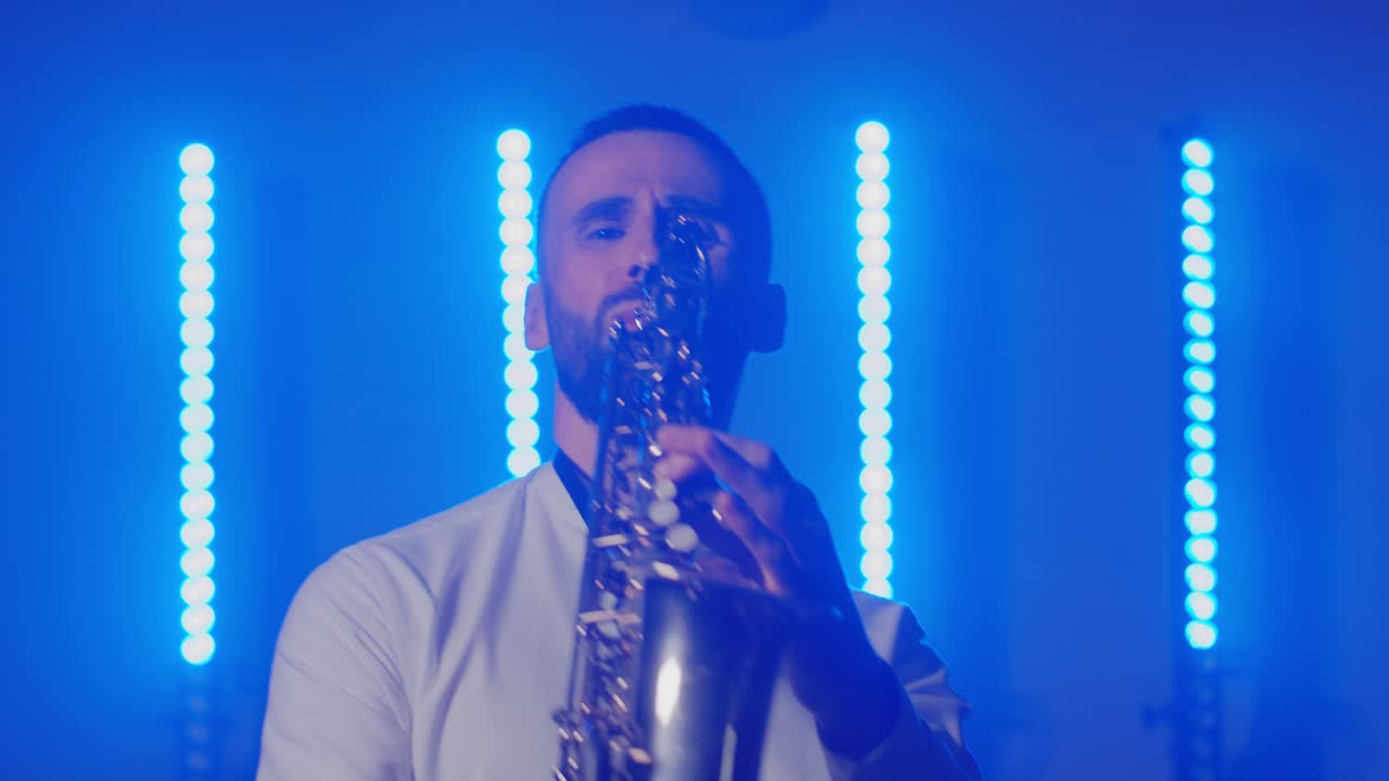 actuación en vivo del saxofonista hombre con saxofón, bailando en el escenario del músico de concierto con luces