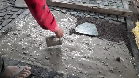 trabajadores que realizan la aplicación del suelo y vierten agua de cemento sobre el hormigón para fijar piedras pequeñas