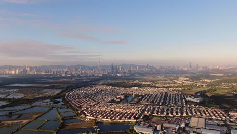 hong kong and shenzhen border line over hong kong rural houses with shenhzen skyline in the horizon, aerial view