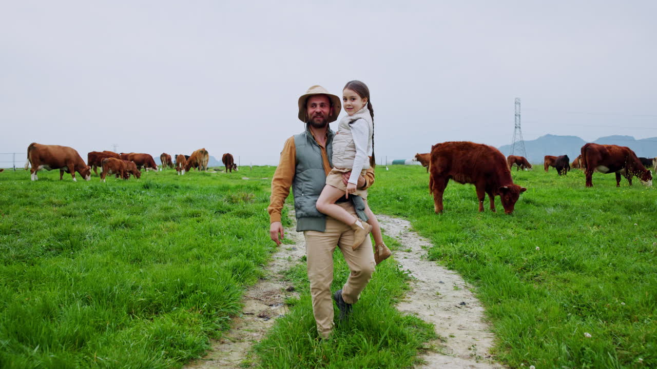 Pai carregando a filha em pasto com vacas