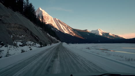 Aufnahme-Aus-Der-Perspektive-Einer-Fahrt-Entlang-Einer-Schneebedeckten-Straße-Mit-Dramatischem-Berg-In-Der-Ferne