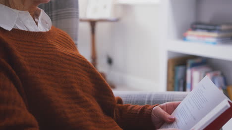 Nahaufnahme-Einer-älteren-Frau,-Die-Zu-Hause-Im-Sessel-Sitzt-Und-Ein-Buch-Liest