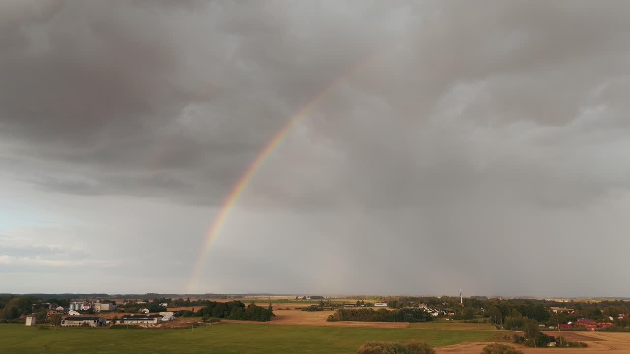 The Rainbow Over the Green Field After Storm With Rain, During Outumn, Aerial View Under Heavy Clouds Before Thunderstorm. Agriculture Landscape Many Crop Fields. Aerial 4k Shot