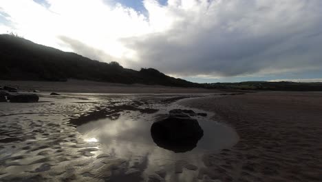 time lapse shimmering sunset beach rock pool clouds passing above woodland coastline