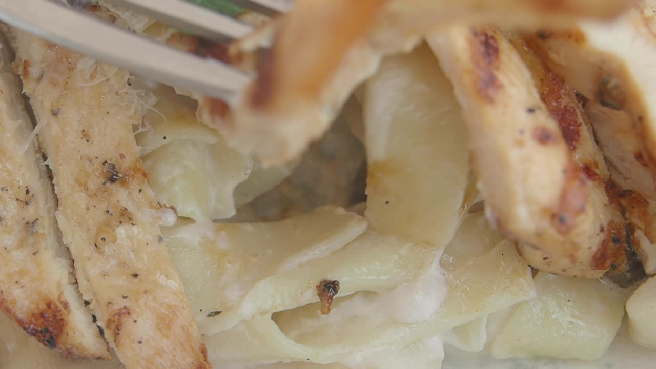 Close-up of Grilled Chicken and Creamy Pasta with a Fork