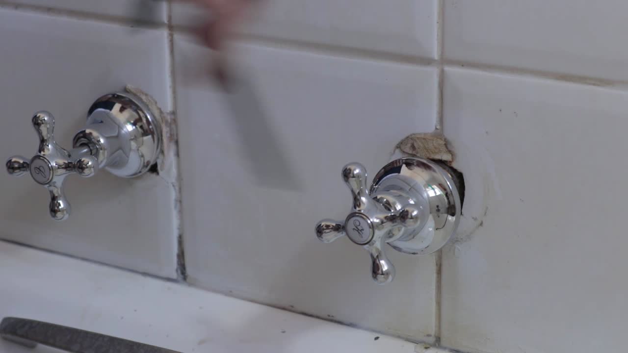 一個男人穩定地拍攝,確保一個水龍頭固定在牆上