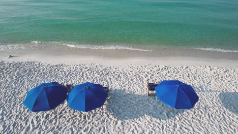 aerial view of blue umbrellas on white sand beach pensacola beach on the clear waters of the gulf of mexico on a clear sunny summer day