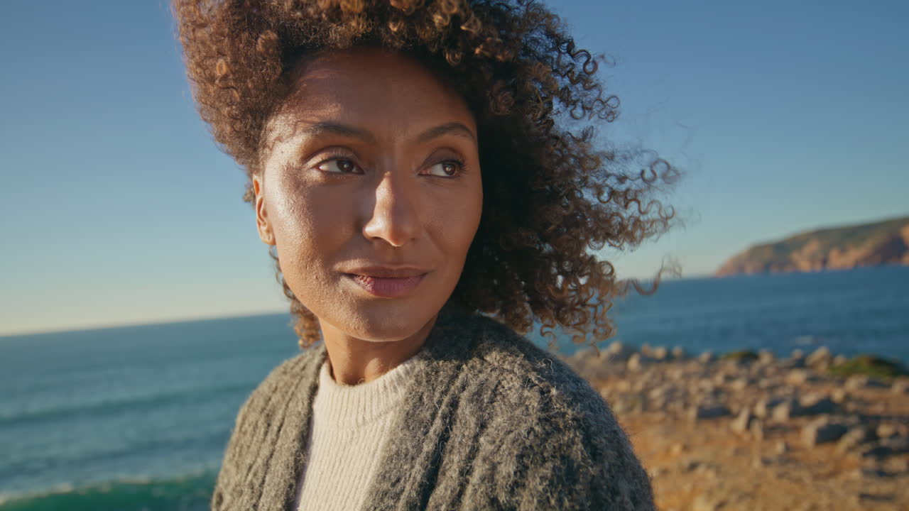 Curly hair girl dreaming sea shore closeup. Calm woman enjoying wind thinking