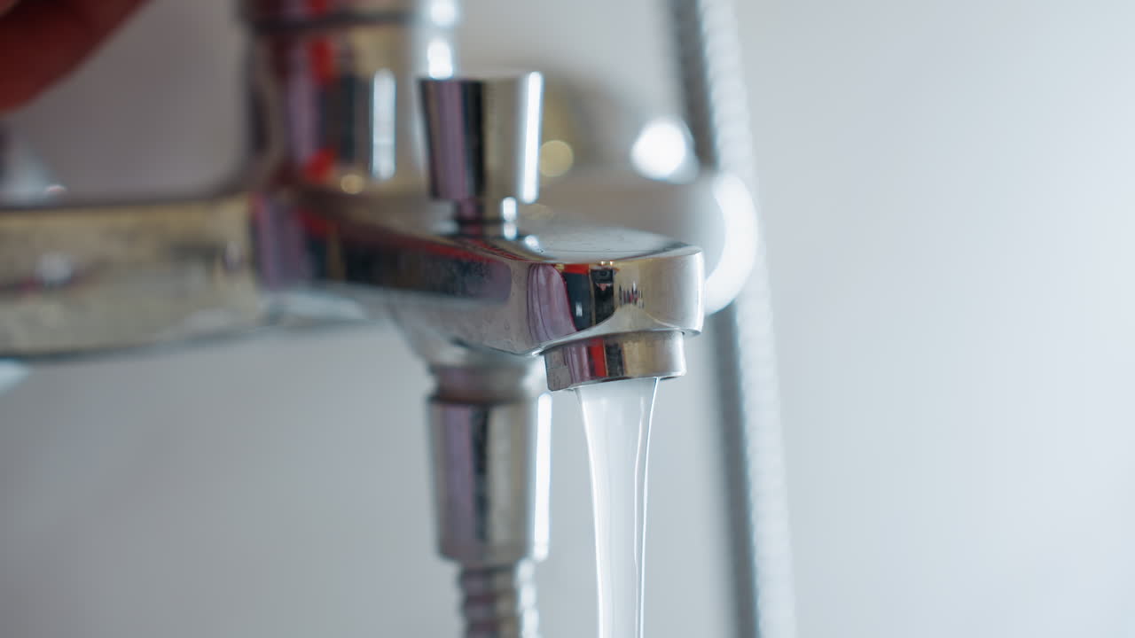 Close up of water rushing out from shiny chrome faucet tap in bathroom, illustrating household plumbing, utility use, hygiene and daily lifestyle with detail focus on running clear stream