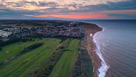 Drone&#039;s perspective of Skegness coastal town during summer sunset, highlighting holiday park, beach, sea, and caravans in scenic views
