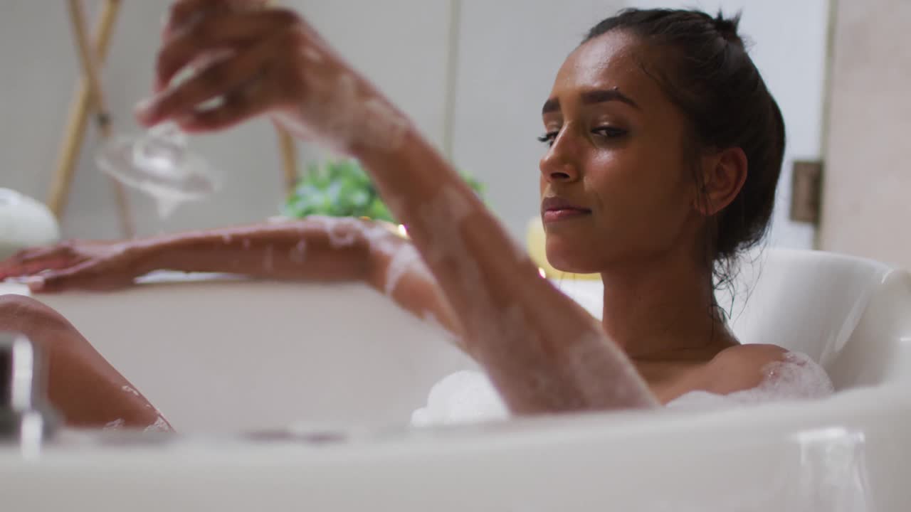 Mixed race woman lying in a bathtub at home