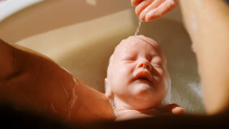 Mother-giving-her-baby-boy-a-bath-in-bathroom-4k