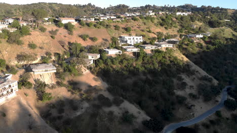 aerial flyby of homes on stilts hanging off cliffs of a mountain overlooking a valley city