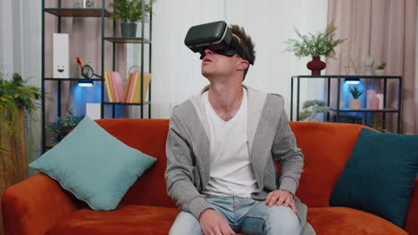 joven usa gafas de realidad virtual en casa, disfrutando del concepto de video moviendo las manos en el aire