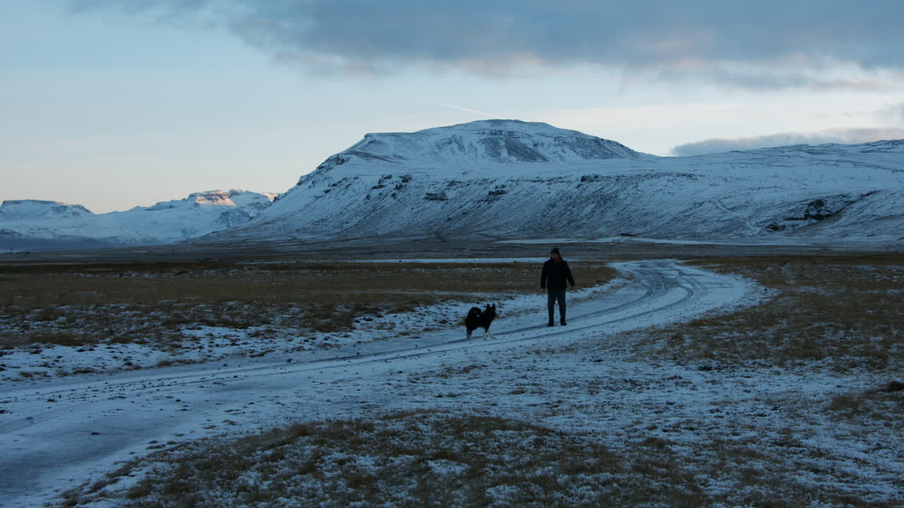 Stable shot shows man playing with his dog at sunset in a winter mood